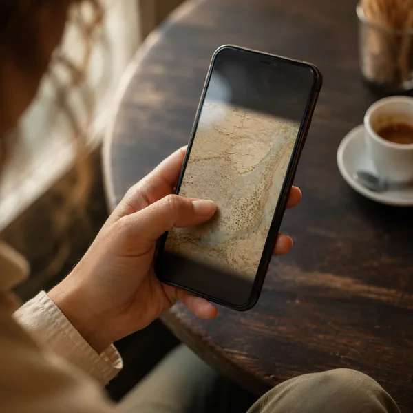 Close-up of a hand holding a phone with a pale map on screen